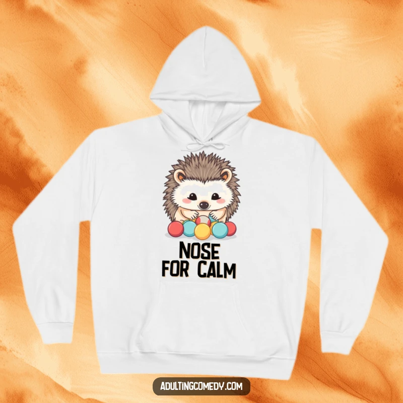Funny Hedgehog Hoodie: A determined hedgehog carefully sorts miniature stress balls with its nose, offering cozy humor and a calming presence.